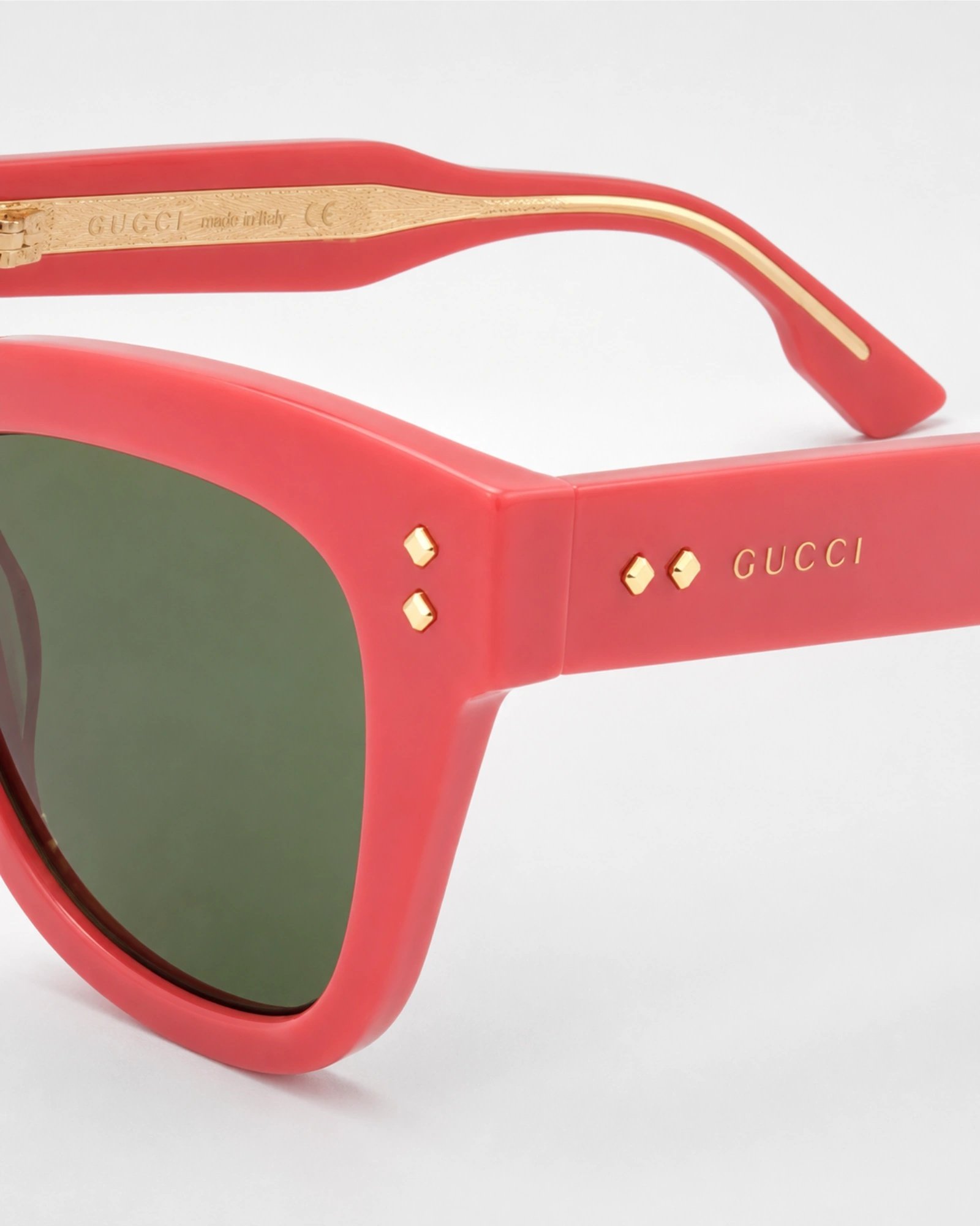 Κοντινή λεπτομέρεια Gucci GG1082S 004 coral γυαλιά ηλίου με χρυσό Gucci logo και πράσινο φακό
