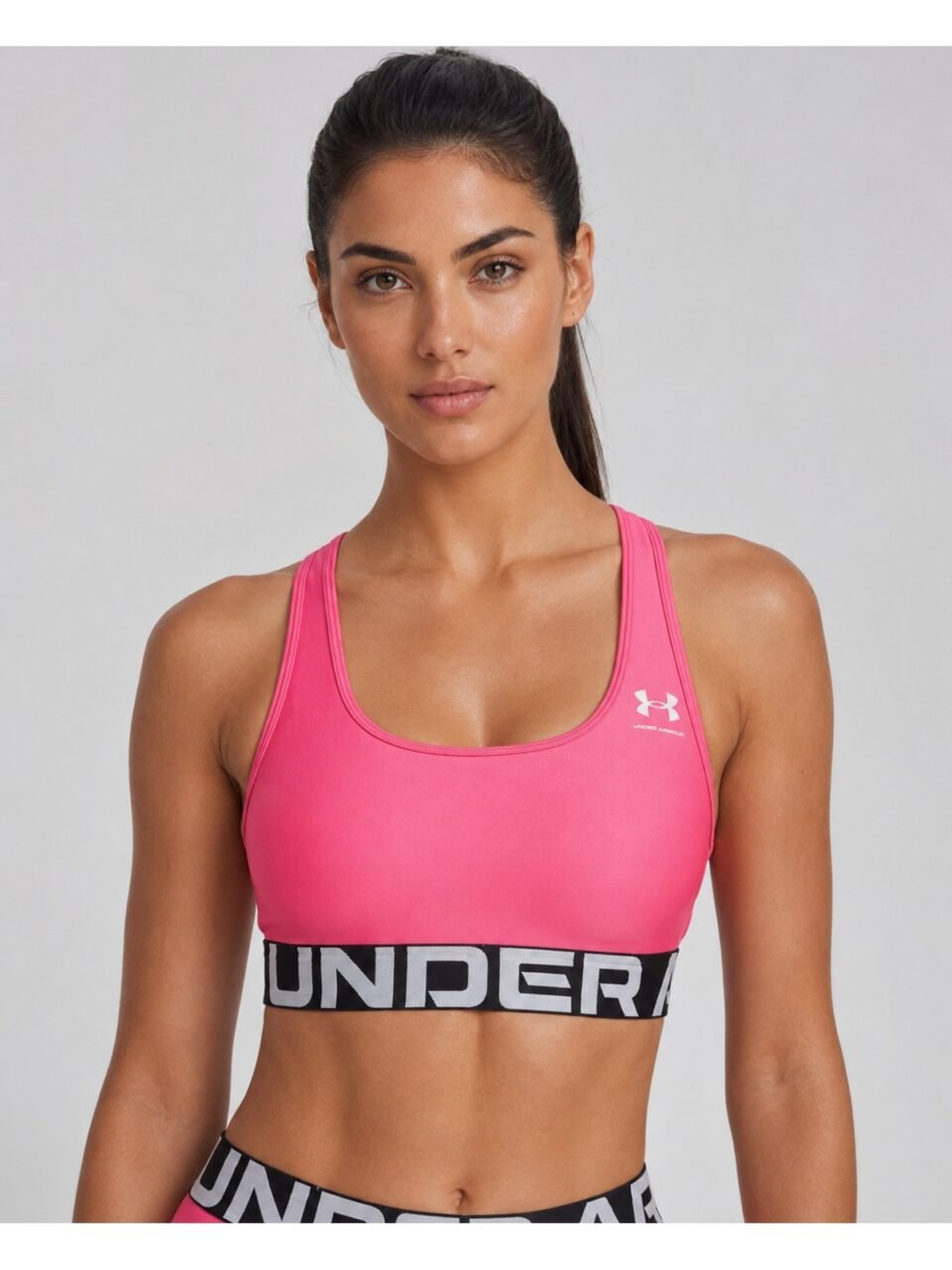 Μοντέλο φοράει Under Armour HeatGear Mid Branded ροζ αθλητικό μπουστάκι