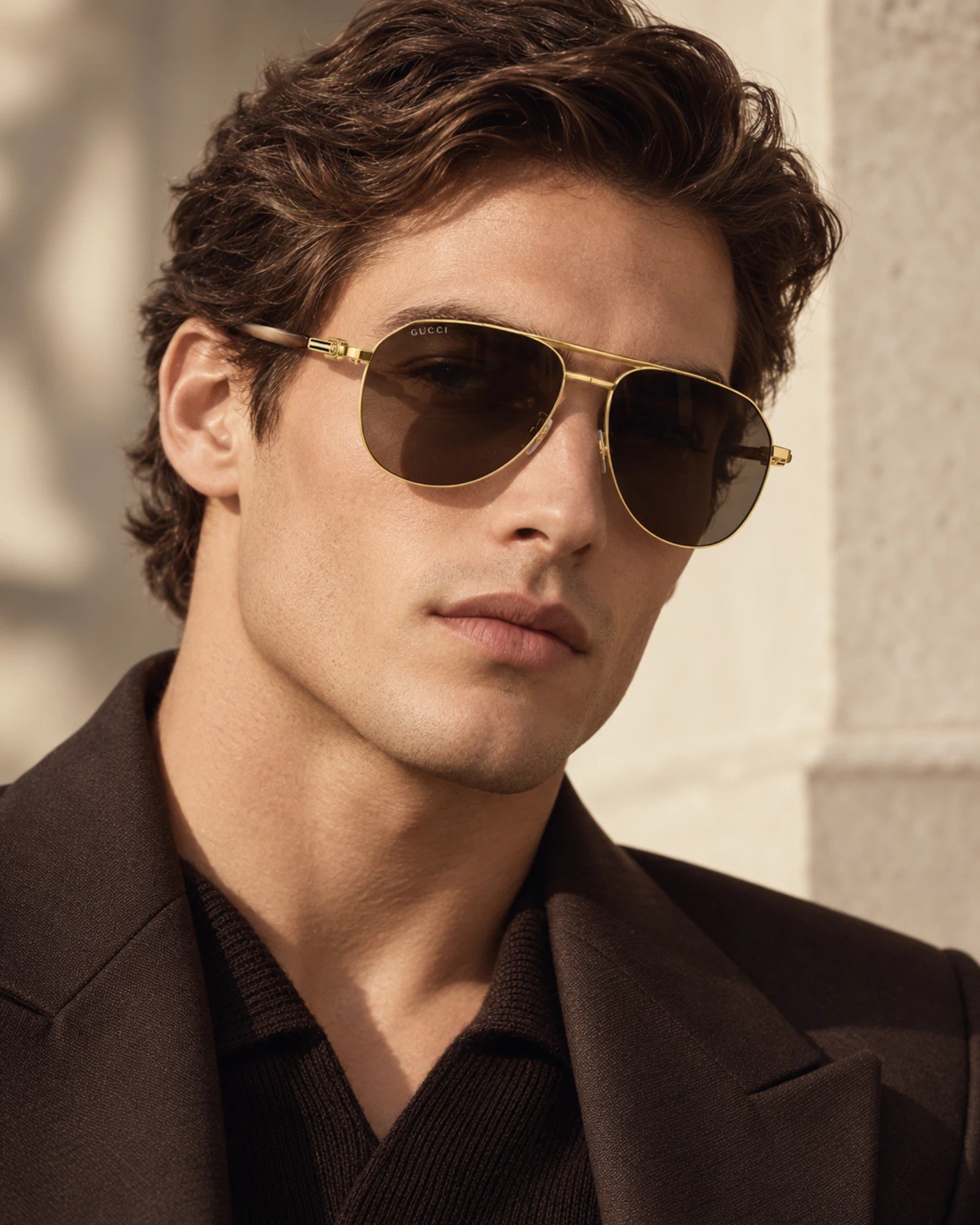μοντέλο που φοράει γυαλιά ηλίου Gucci GG1220S 002 σε χρυσό μεταλλικό σκελετό με καφέ φακούς και καφέ βραχίονες
